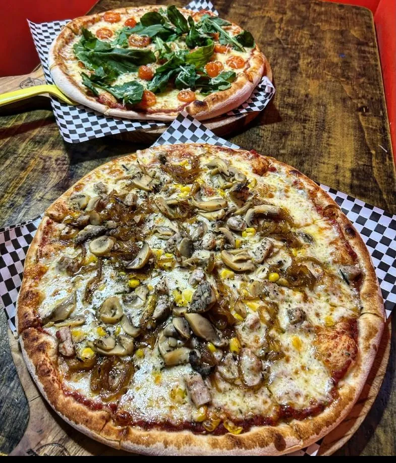 Dos pizzas recién horneadas sobre la mesa de madera