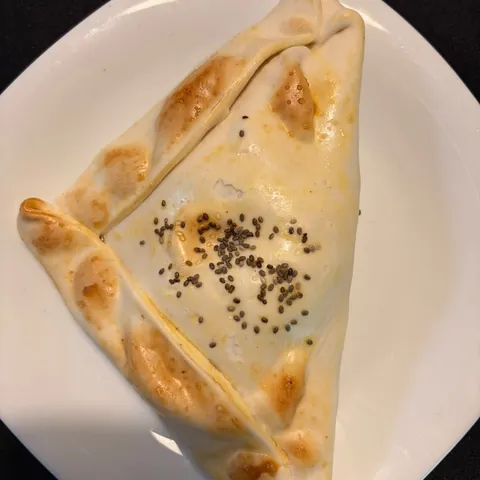 Empanada de choclo, queso, tomate y albahaca recién horneada